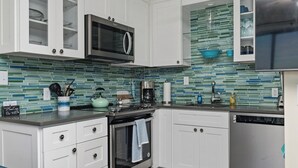 A modern kitchen with white cabinetry, a stainless steel oven, a microwave, and a dishwasher. - Beachfront Boardwalk Escape (Carolina Beach)
