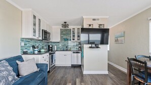 A compact living space with a kitchenette, a sofa, and a dining area. - Beachfront Boardwalk Escape (Carolina Beach)