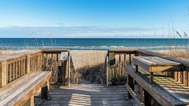 A wooden boardwalk leading to a beach with a 'No Smoking' sign. - Beachfront Boardwalk Escape (Carolina Beach)