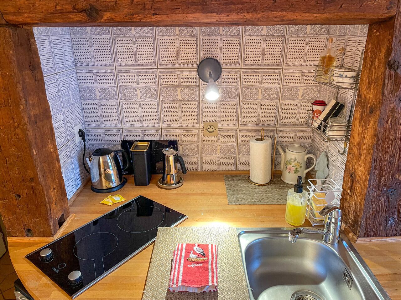 Une cuisine compacte dotée d’un crédence décorée, d’une machine à café, d’une bouilloire, d’un grille-pain et d’un évier.
