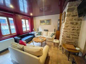 A cozy living room with a stone wall, a fireplace, and a chessboard.