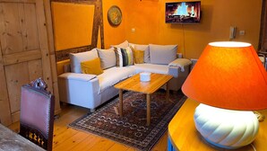 A cozy living room with a sofa, a coffee table, and a lamp. - La Maison Bleue - Historic house in the heart of Riquewihr. "Le Renard" 2-guest apartment (Riquewihr)