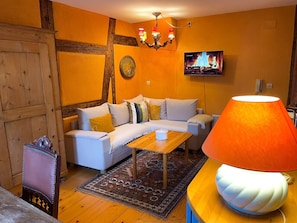 A cozy living room with a sofa, a coffee table, and a lamp. - La Maison Bleue - Historic house in the heart of Riquewihr. "Le Renard" 2-guest apartment (Riquewihr)