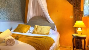 A bedroom with a canopy bed, a bedside table with a lamp, and a rolled towel on the bed. - La Maison Bleue - Historic house in the heart of Riquewihr. "Le Renard" 2-guest apartment (Riquewihr)