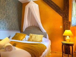 A bedroom with a canopy bed, a bedside table with a lamp, and a rolled towel on the bed. - La Maison Bleue - Historic house in the heart of Riquewihr. "Le Renard" 2 guest flat (Riquewihr)