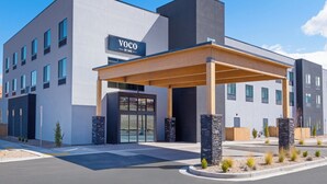 A modern hotel with a covered entrance, a sign reading "VOCO BY IHG", and a parking lot in front. - voco Moab by IHG (Moab)