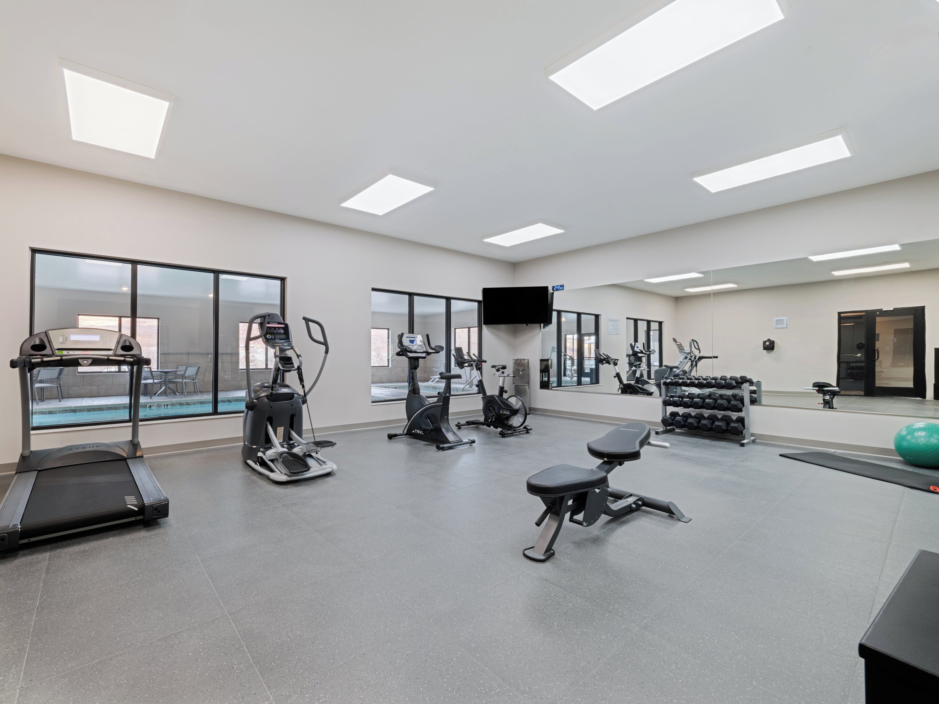 A gym with treadmills, elliptical machines, and free weights.