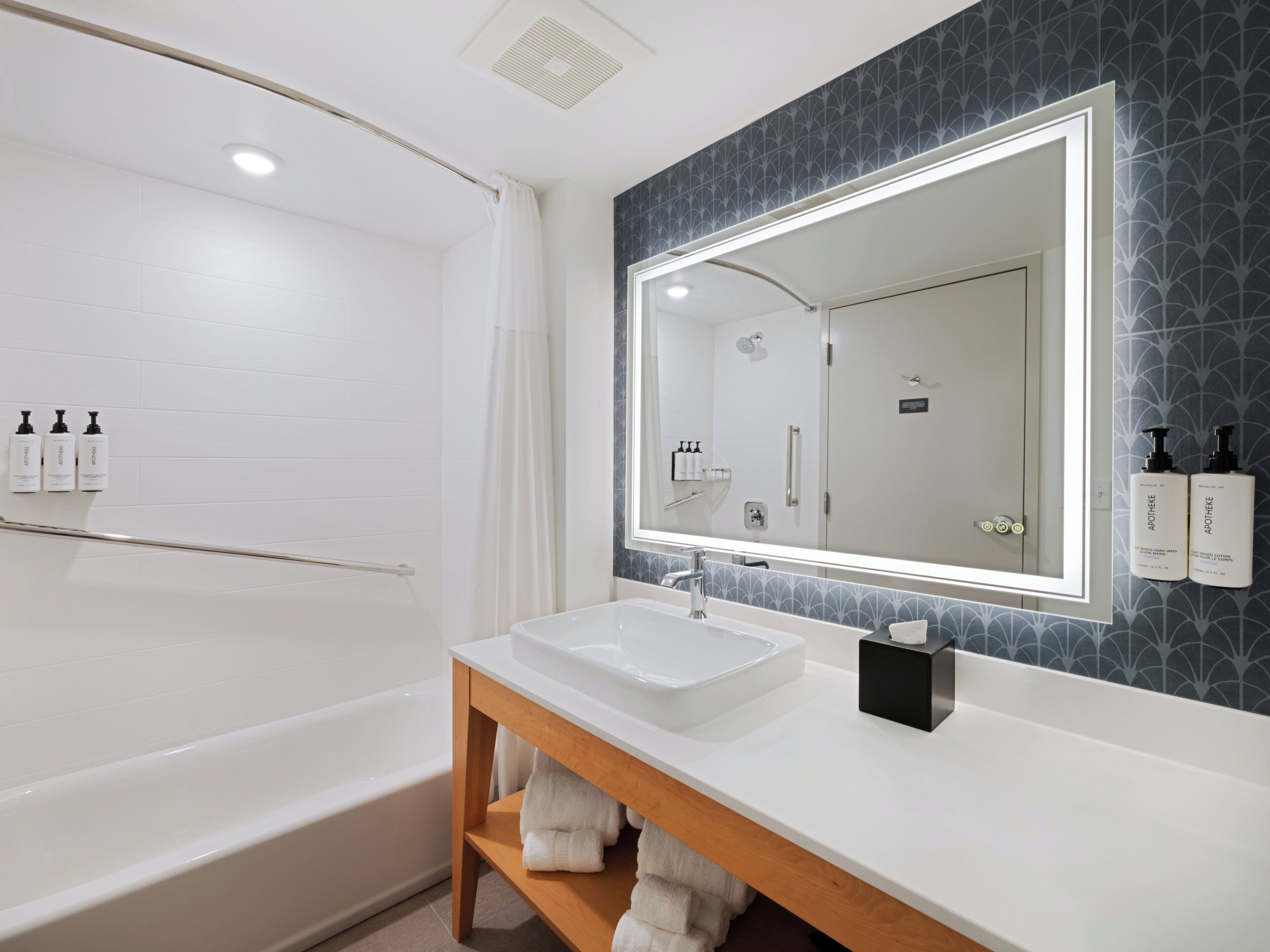 Un baño moderno con una bañera blanca, un espejo grande y un lavabo con tocador.