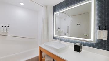 Un baño moderno con una bañera blanca, un espejo grande y un lavabo con tocador.