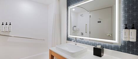 Une salle de bain moderne avec une baignoire blanche, un grand miroir et un meuble-lavabo.