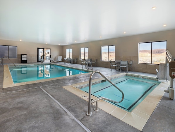 An indoor swimming pool with two lanes, sunlit windows, and a desert view.