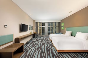 Habitación de hotel con una cama grande, un escritorio con silla, televisión y ventana con vista a la ciudad.
