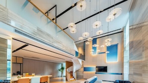 Amplia sala de estar con diseño moderno, que incluye zona de comedor, asientos y una escalera.