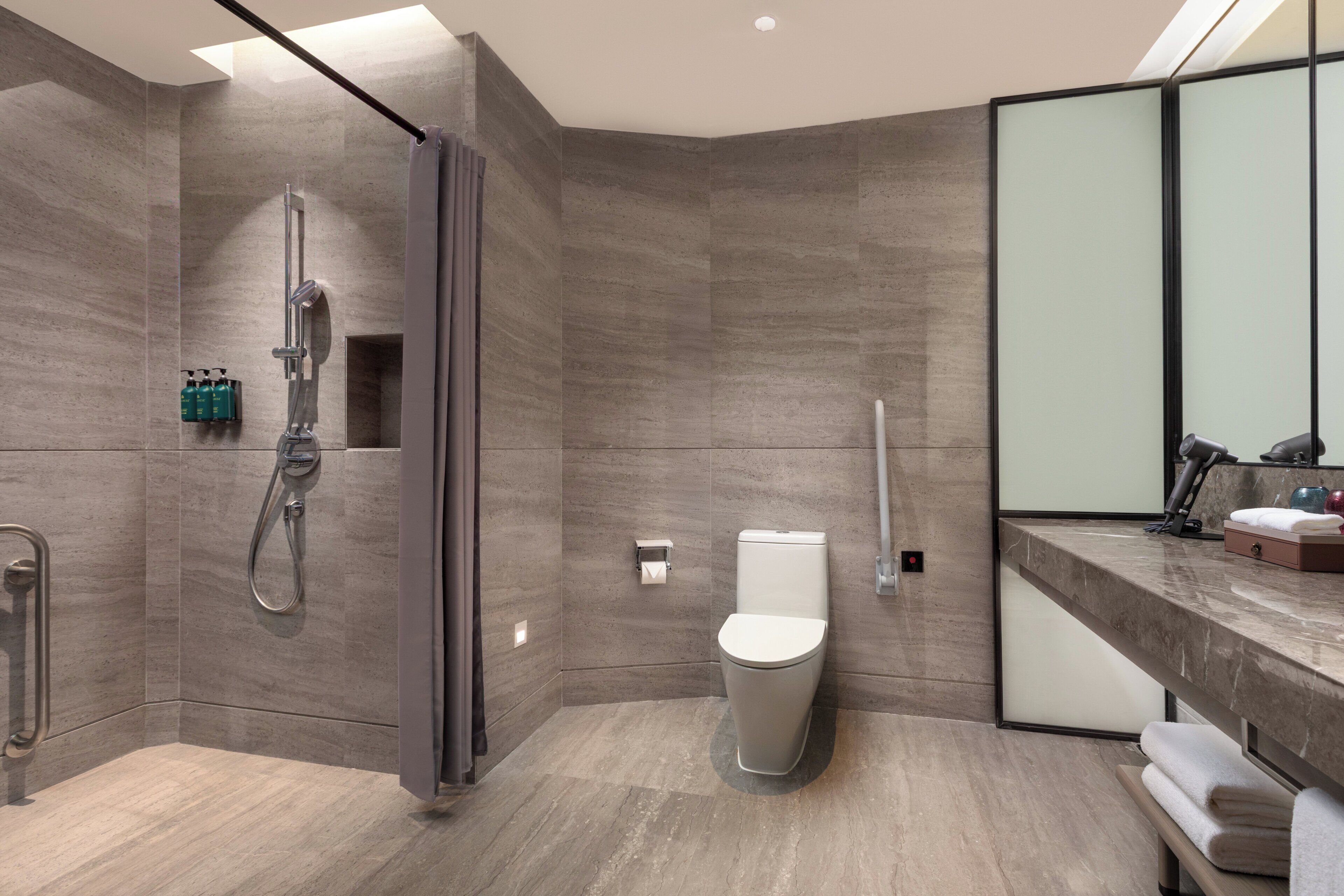 A modern bathroom with a shower, toilet, and vanity with a mirror.