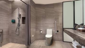 A modern bathroom with a shower, toilet, and vanity with a mirror.