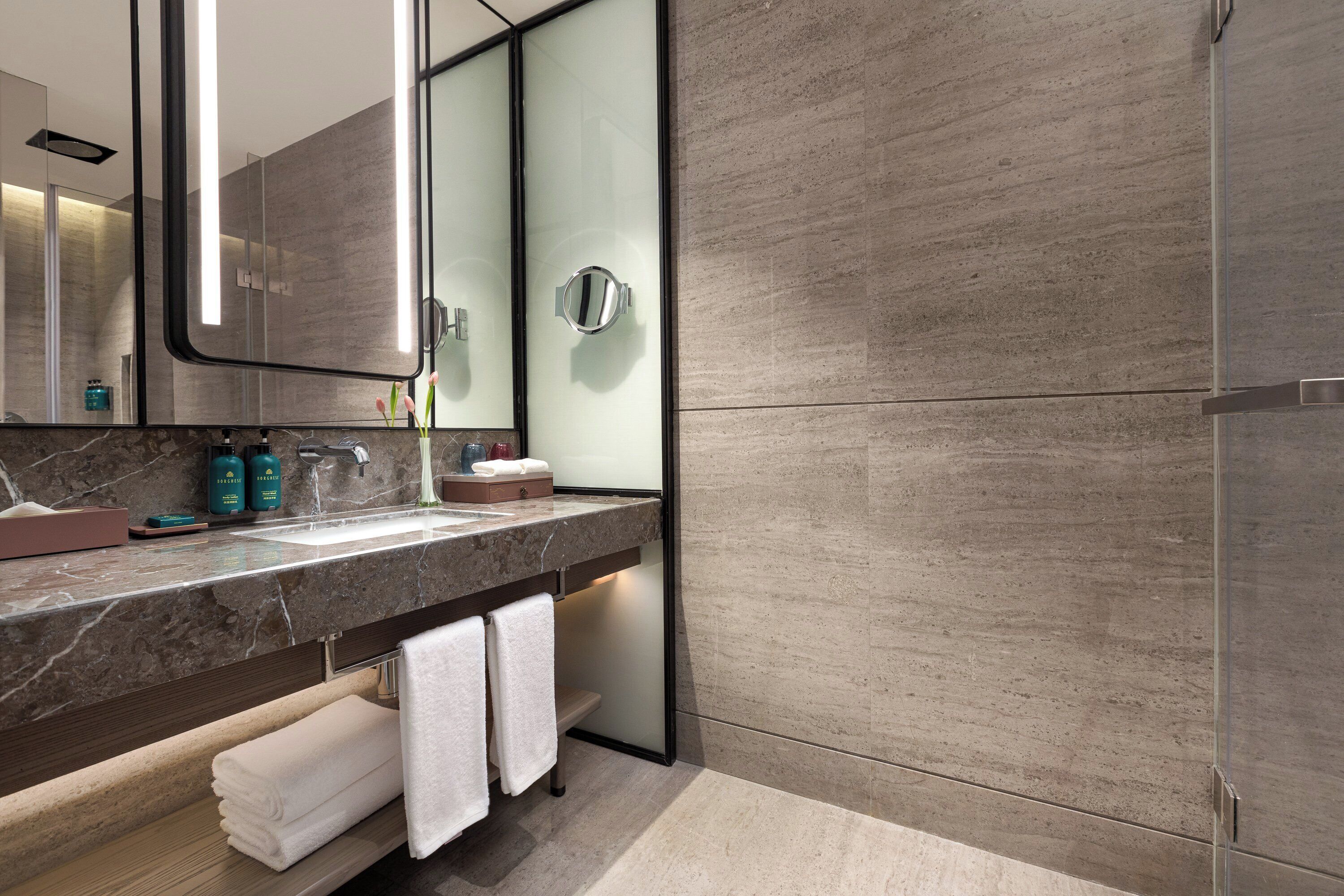 Un bagno moderno con un piano in marmo, uno specchio grande e una cabina doccia in vetro.