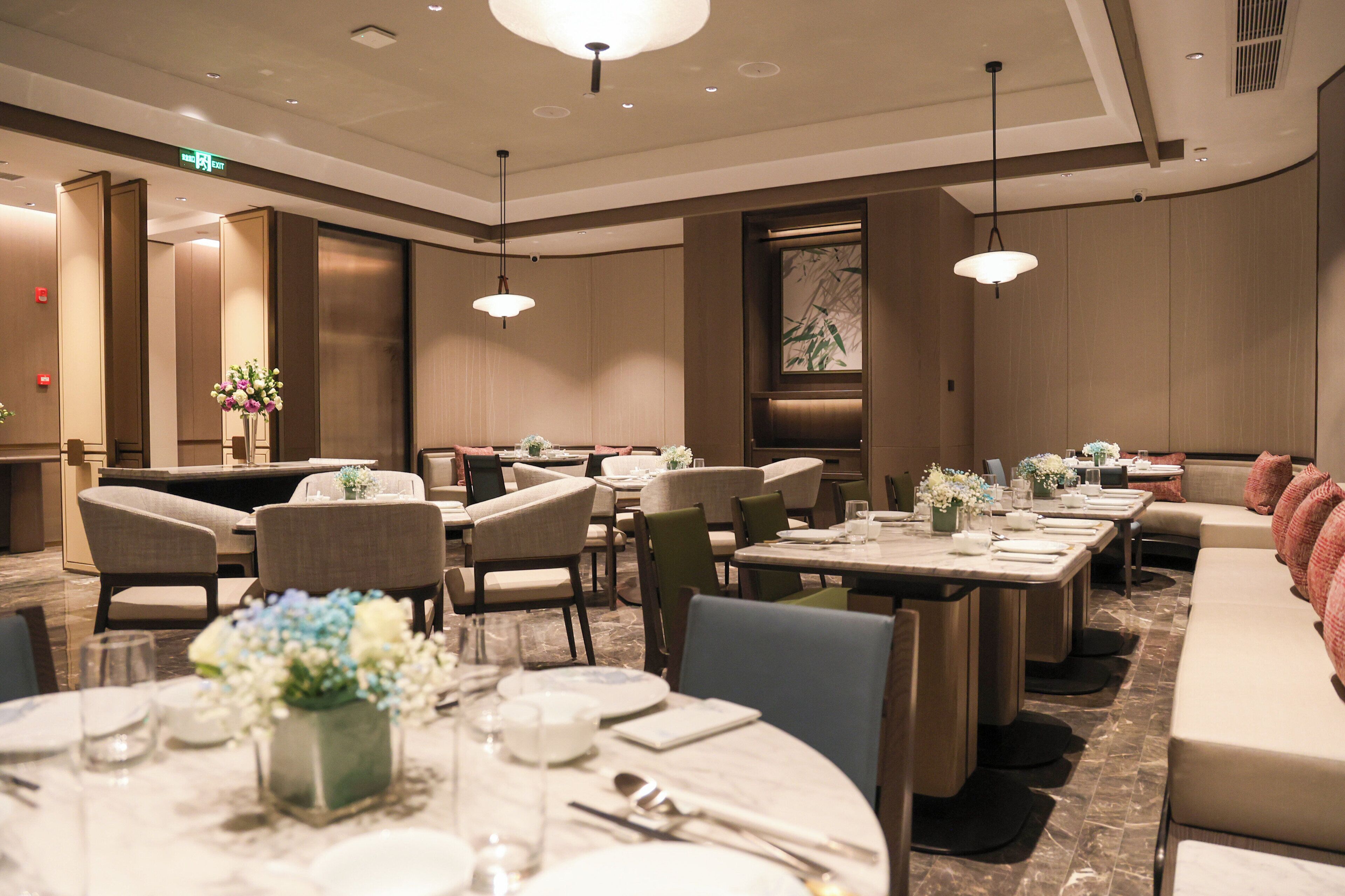 A hotel dining area with multiple tables, chairs, and a long bench.