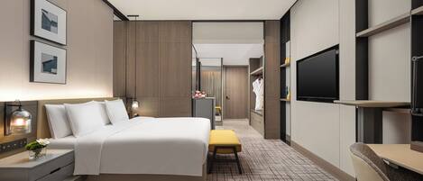 Una habitación de hotel moderna con una cama grande, mesitas de noche, un televisor y un baño visible a través de una puerta abierta.
