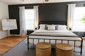 A bedroom with a black headboard, white bedding, two bedside tables with lamps, a framed picture on the wall, and a large window with curtains. - "The Dawning House" - Peaceful Modern Stay w/ Yard (Georgetown)