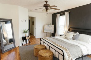 A bedroom with a bed, a ceiling fan, a large mirror, a painting on the wall, and a window with curtains. - "The Dawning House" - Peaceful Modern Stay w/ Yard (Georgetown)