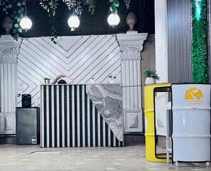 A reception desk with a black and white striped backdrop, a marble accent, and a yellow trash bin. - Danda Moon Pyramids Hotel (Giza)