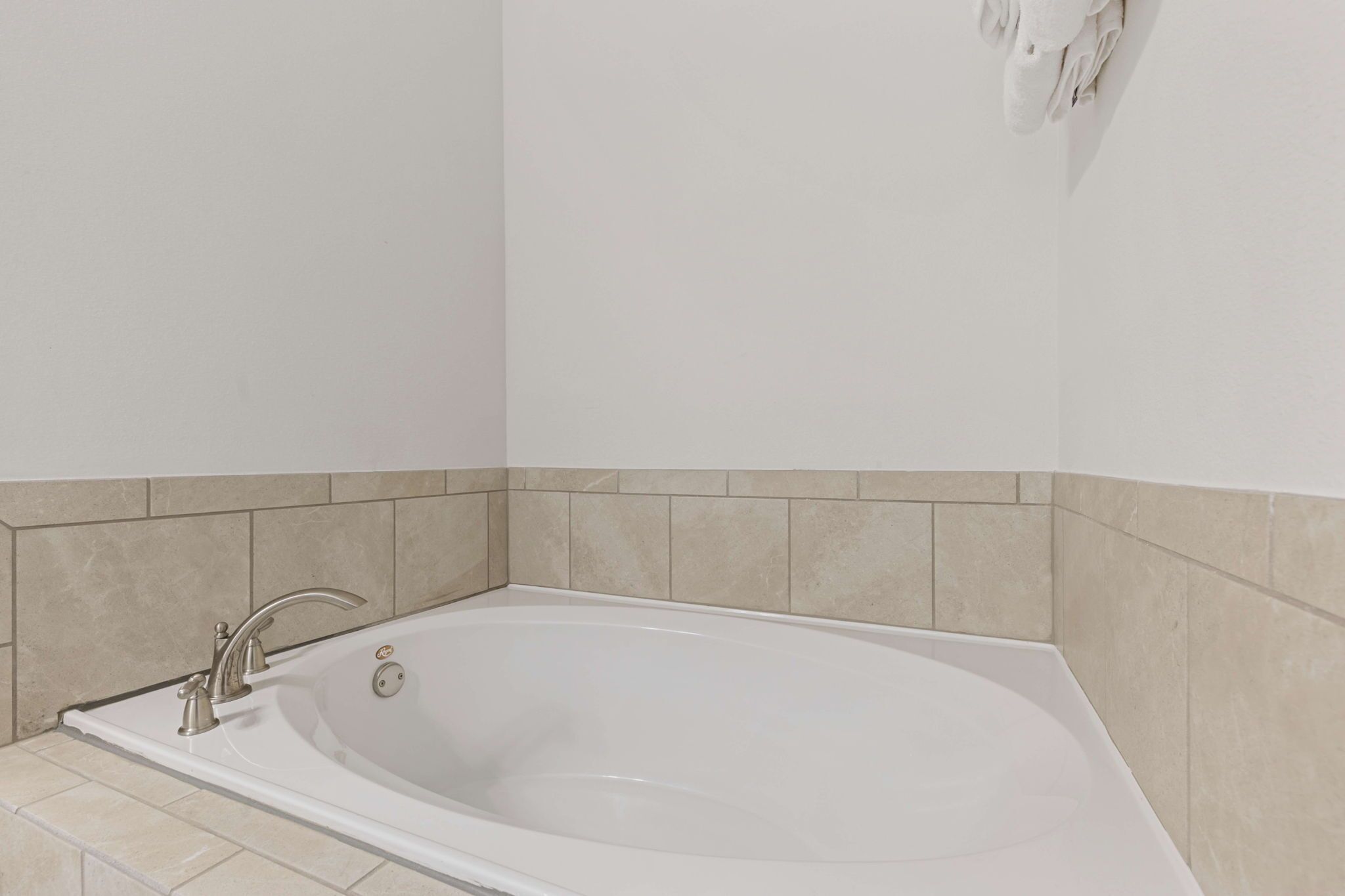 Een moderne badkamer met een vrijstaand bad, betegelde wanden en een neutraal kleurenschema.