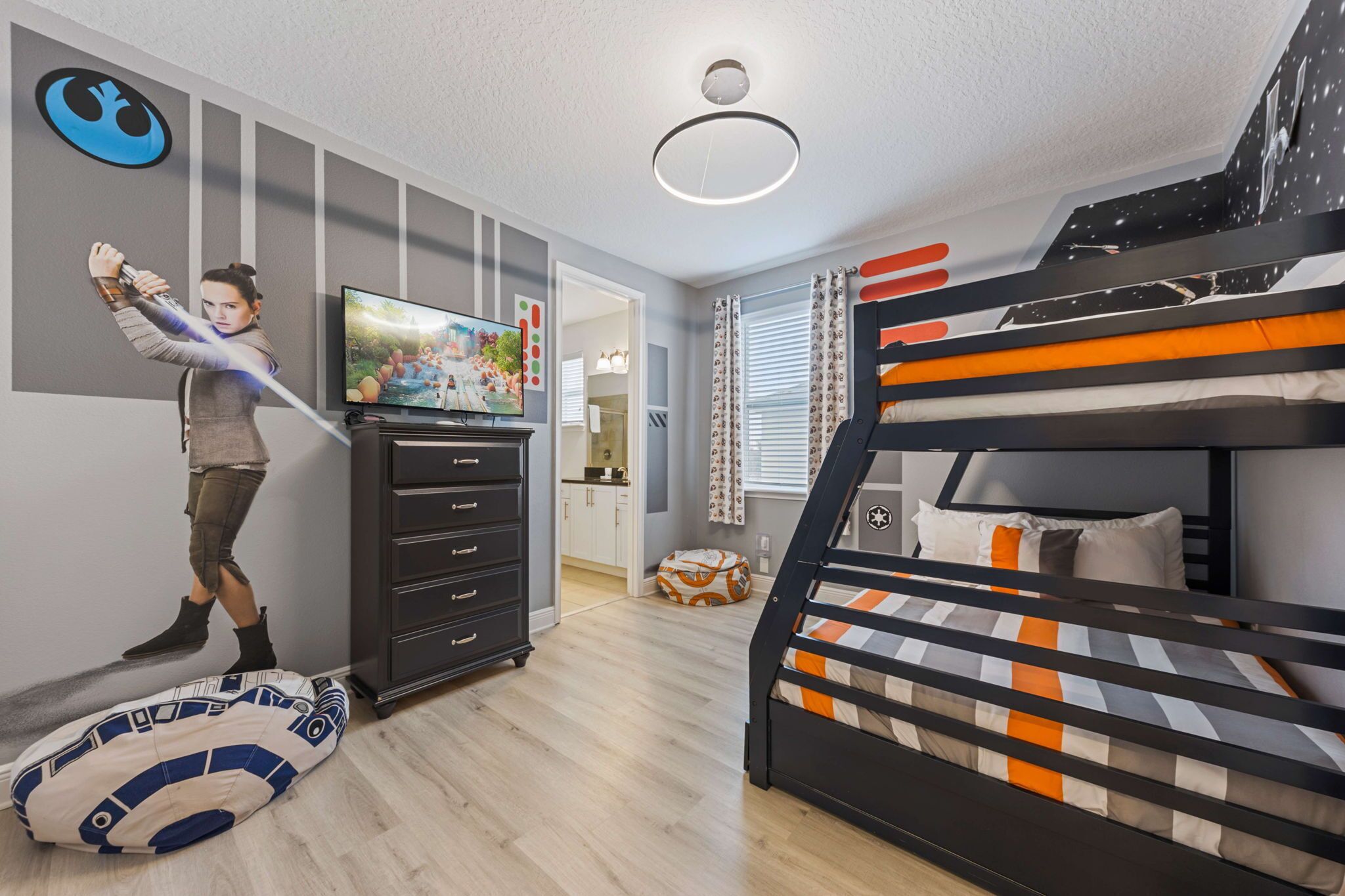A bedroom with a bunk bed, a TV, a Star Wars-themed pillow, and a Star Wars poster on the wall.