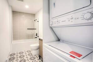 Compact bathroom with shower enclosure, toilet, and washing machine.