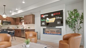 A modern living room with a flat-screen TV displaying streaming services, a fireplace, and leather armchairs. - Pow Turns Eden Pt B204 | Powder Mtn Ski Retreat (Eden)