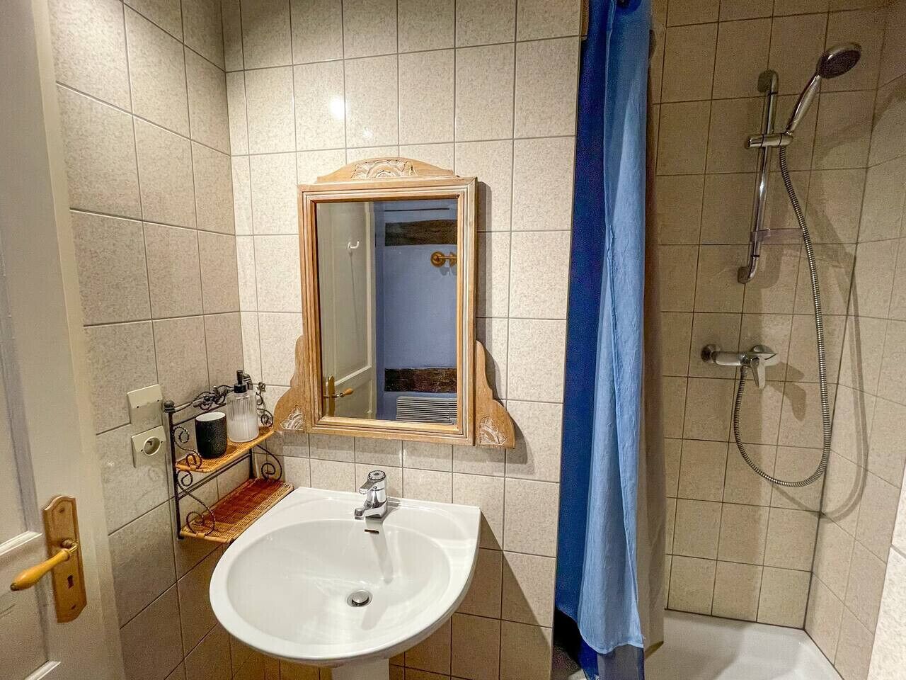 Une salle de bain avec un lavabo, un miroir, une douche et des murs carrelés.