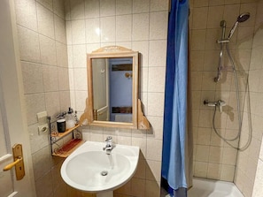 A bathroom with a sink, mirror, shower, and tiled walls. - La Maison Bleue - Historic house in the heart of Riquewihr. "Le Hérisson" 2-guest apartment (Riquewihr)