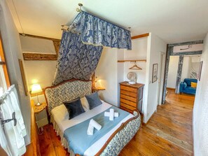 A bedroom with a bed, bedside tables, a dresser, and a hanging light fixture. - La Maison Bleue - Historic house in the heart of Riquewihr. "Le Hérisson" 2-guest apartment (Riquewihr)