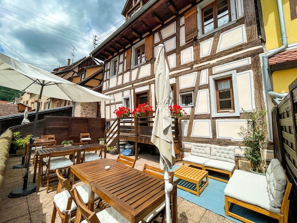 A traditional half-timbered building with outdoor seating, including wooden tables and chairs, and a sofa.