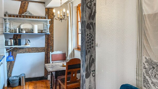 Una cocina compacta con una mesa de madera, una silla y un sofá azul.