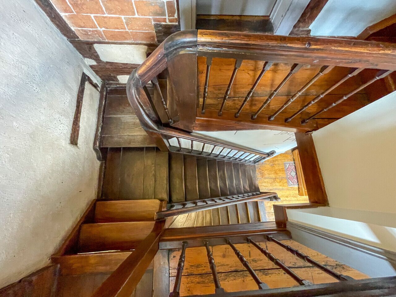 Eine Holztreppe mit Metallgeländern, Ziegelmauern und einem Fenster mit farbigem Glasdekor.