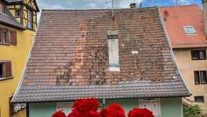 Una casa tradicional con techo inclinado, una ventana pequeña y una chimenea.
