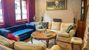 Un salón con un sofá azul, un sofá color beige y una mesa de centro de madera con libros.