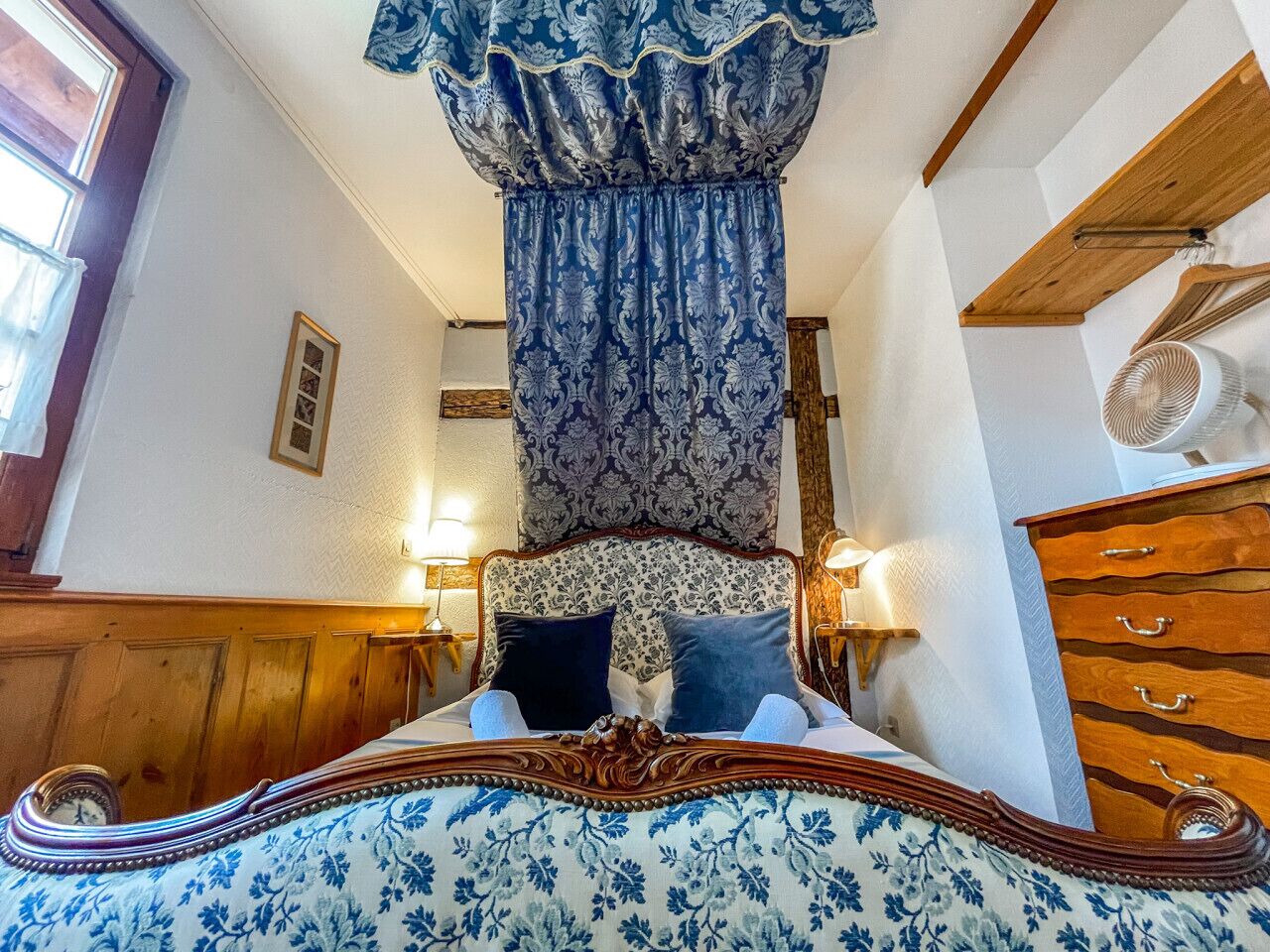 Ein Schlafzimmer mit einem großen Bett, einem Holzkopfende und einem Fenster mit Vorhängen.