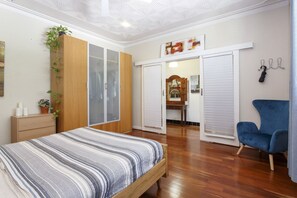 Ein Schlafzimmer mit Bett, Kleiderschrank und blauem Sessel.