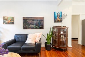 Ein Wohnzimmer mit einem schwarzen Ledersofa, einem Topf mit Pflanze und einem Holzschrank.