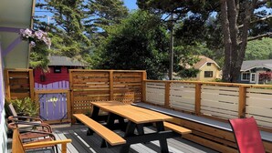 A wooden deck with picnic tables and chairs, surrounded by a wooden fence and trees. - Superb 3-bedroom house with WiFi in Neskowin.   (Neskowin)