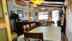A cozy dining area with a wooden table and chairs, a sofa, and a large window with a view. - Superb 3-bedroom house with WiFi in Neskowin.   (Neskowin)