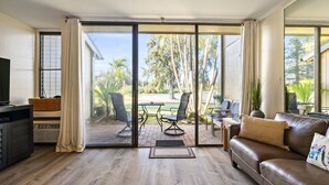 Ein Wohnzimmer mit einer Schiebetür zu einem Außenbereich, der einen Tisch und Stühle bietet.