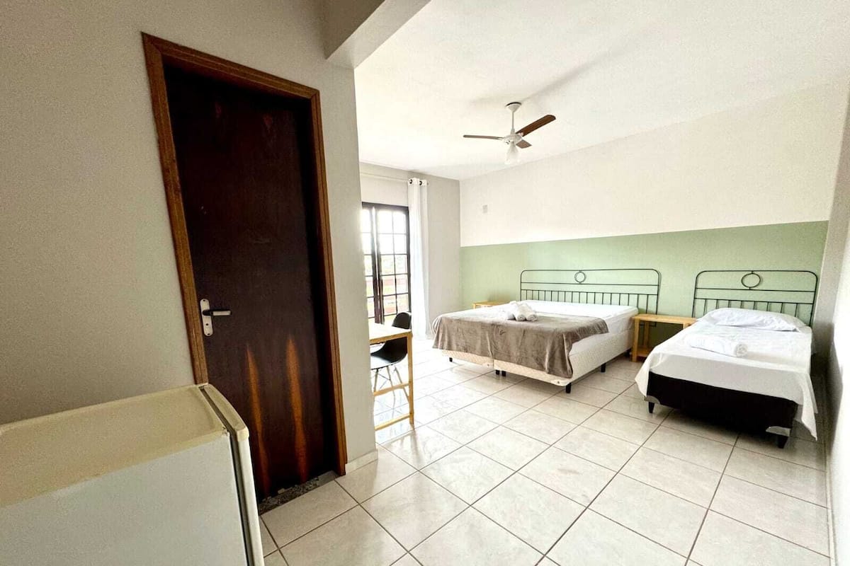A room with two beds, a ceiling fan, and a door.
