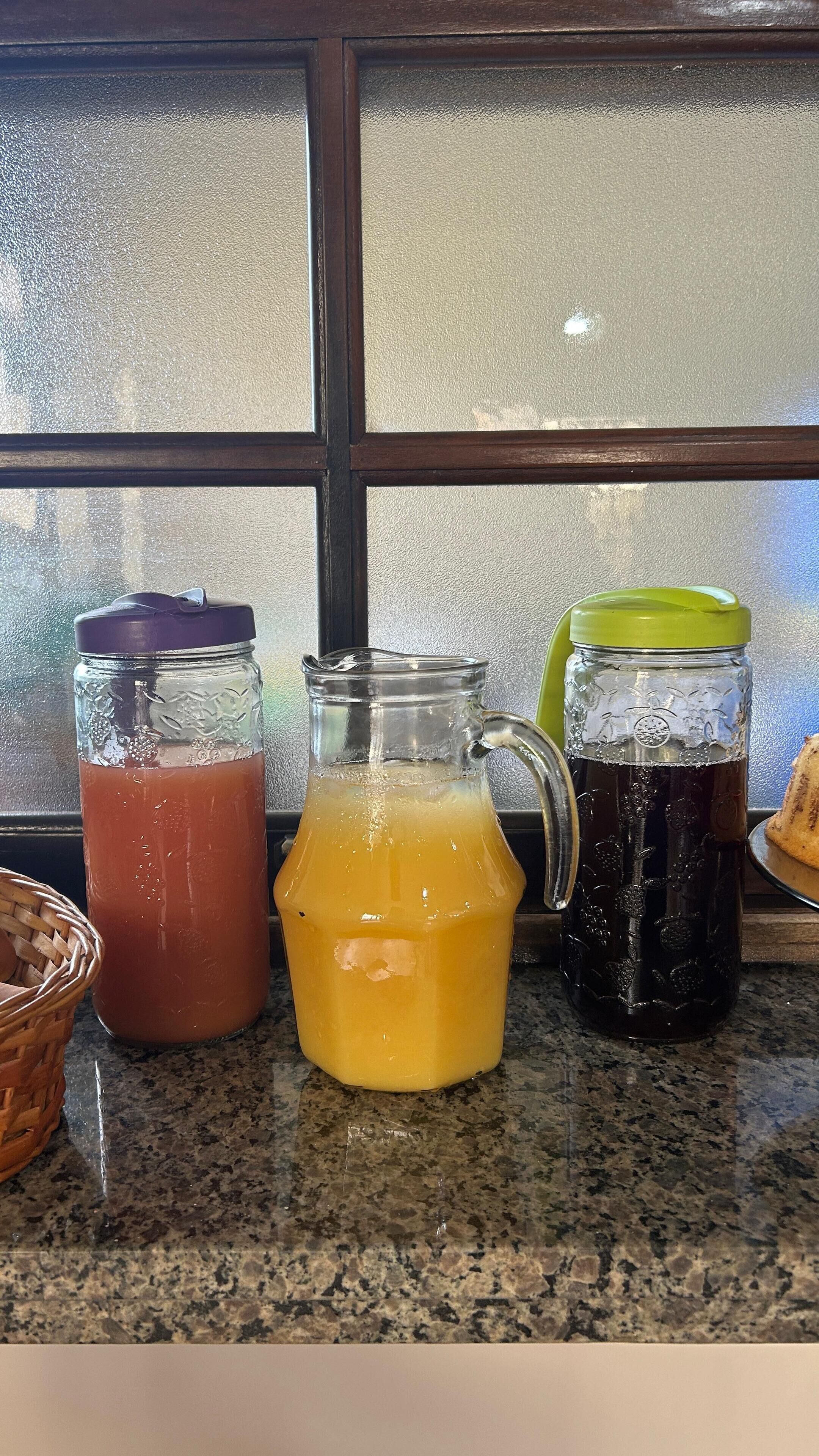 Three glass containers with different colored liquids on a kitchen counter.