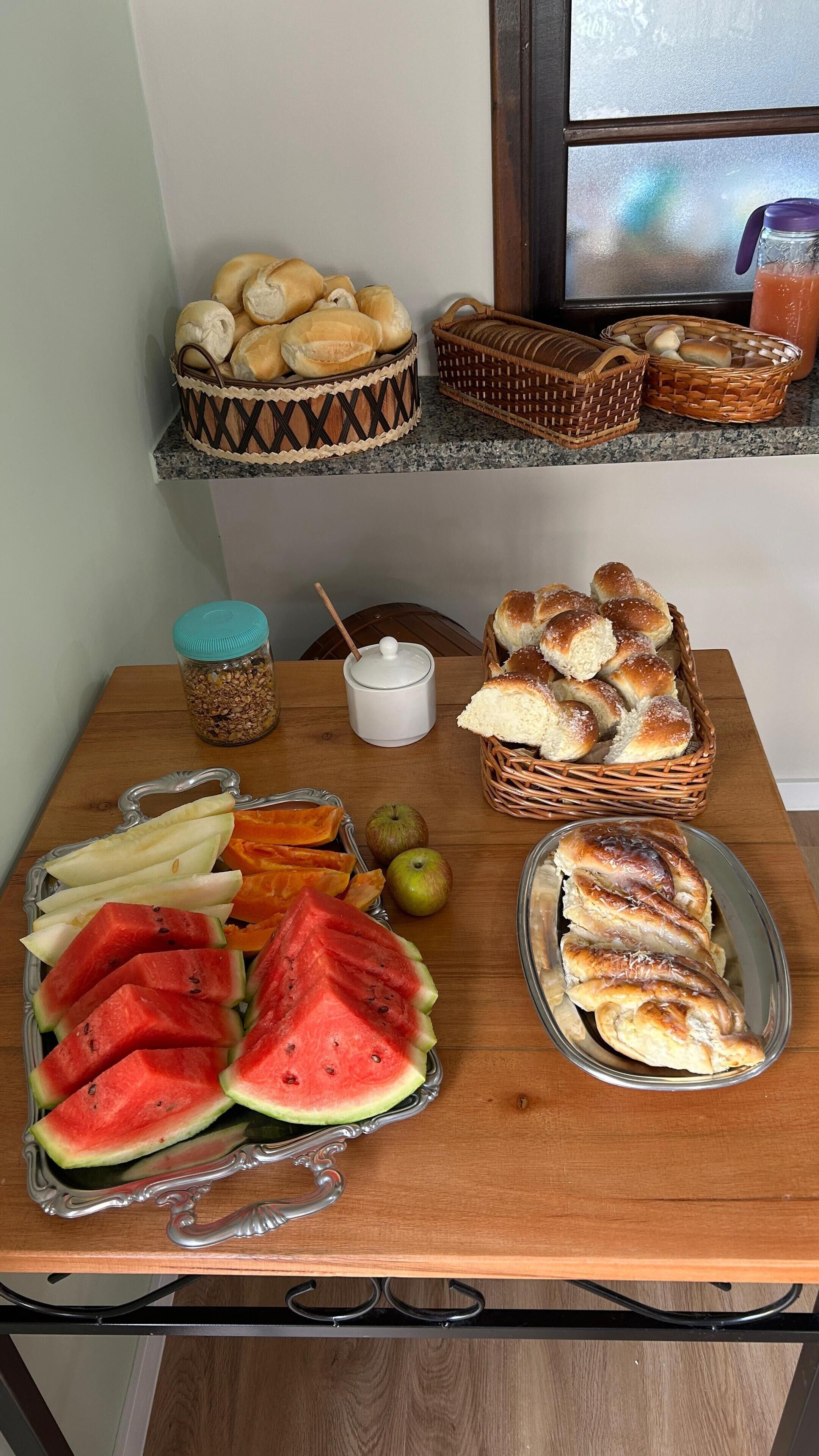 A breakfast table with bread, pastries, and fruit.