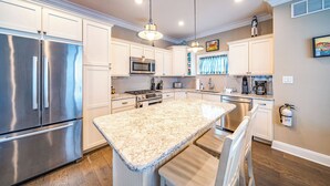 A modern kitchen with stainless steel appliances, granite countertops, and white cabinetry.
