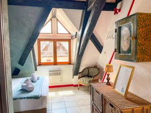 Un dormitorio acogedor en el ático con techo inclinado, una cama con toallas enrolladas, una silla, una mesa con lámpara y un menú enmarcado en la pared.