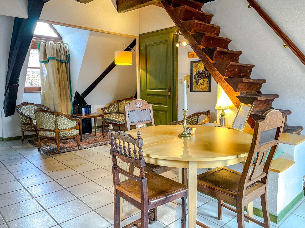 Comedor con una mesa redonda, sillas de madera y una escalera.
