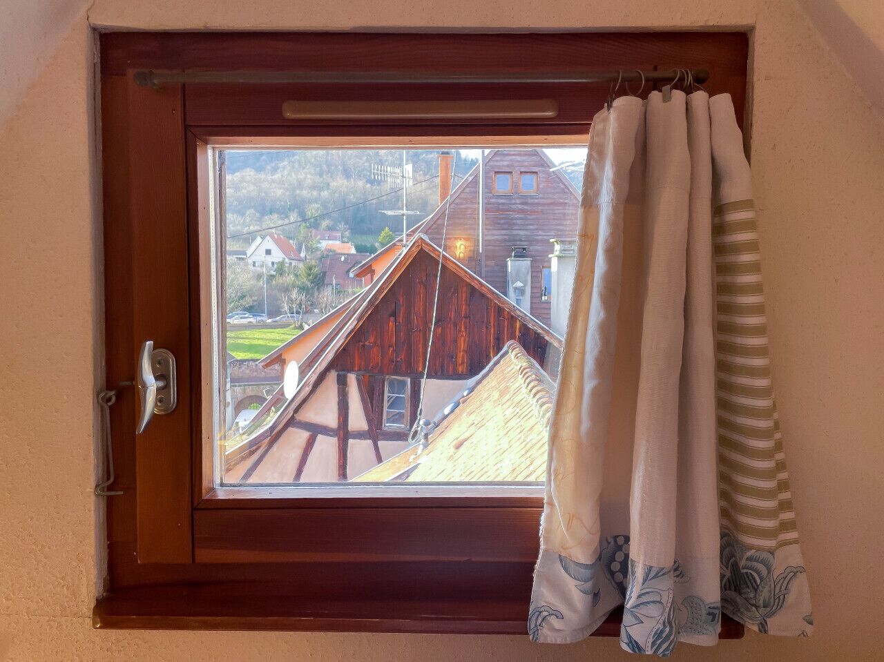 Ein Fenster mit Blick auf traditionelle Holzhäuser und einen klaren Himmel.